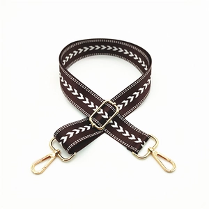Close-up of brown arrow jacquard bag strap with adjustable buckle and gold metal hooks