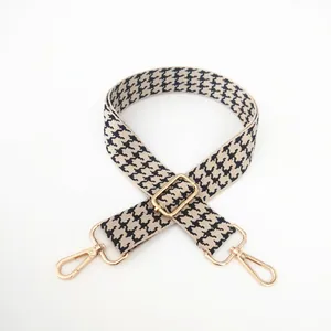 Adjustable houndstooth bag strap with golden metal swivel hooks and thick webbing texture