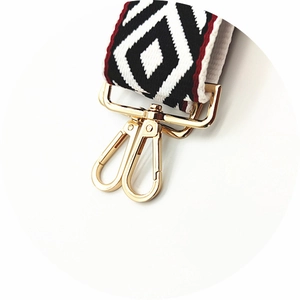 Macro detail of widened geometric pattern bag strap with premium gold metal swivel hooks
