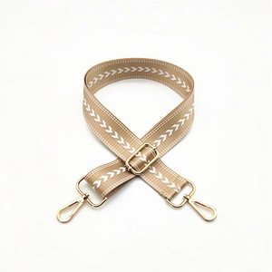 Detail of camel woven bag strap with white arrow pattern and golden metal hardware