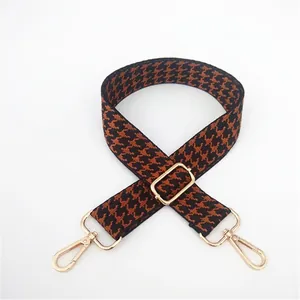Detail of adjustable houndstooth bag strap with gold rotating metal lobster clasps