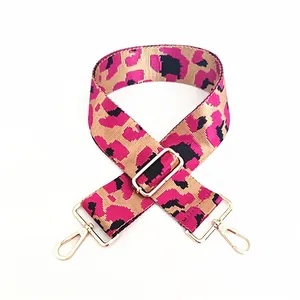 Detail of adjustable leopard print bag strap with pink nylon webbing and gold metal hooks