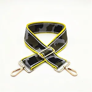 Detail of camouflage bag strap with golden lobster clasps and yellow edge trim