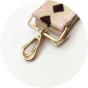 Detail of premium gold swivel hook and colorful geometric diamond jacquard bag strap