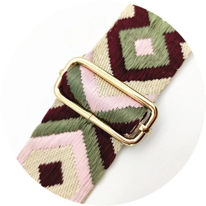 Close-up of ethnic geometric pattern embroidery on bag strap with gold metal buckle
