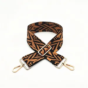 Detail of widened thick woven shoulder strap with black-brown pattern and gold metal hooks