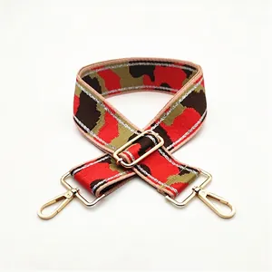 Detail of red and green camouflage wide bag strap with gold metal hooks and silver glitter edges