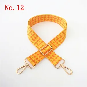 Detail of adjustable yellow houndstooth woven bag strap with light gold metal swivel hooks