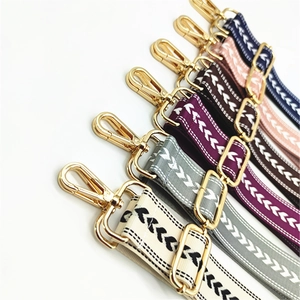 Detailed view of adjustable crossbody bag straps with geometric patterns and gold metal buckles