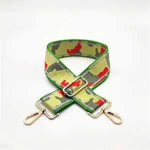 Detailed macro view of wide camouflage canvas bag strap with gold metal hardware