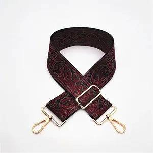 Close-up of red and black paisley jacquard bag strap with gold metal lobster clasps