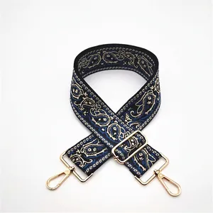 Detail of bohemian paisley woven strap with golden adjustable buckles and swivel hooks