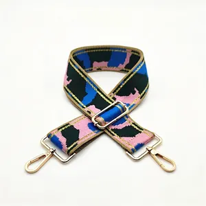 Detail of adjustable camouflage bag strap with pink and blue patterns and gold hardware