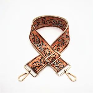 Detail of adjustable paisley fabric strap with gold metal hooks for handbags