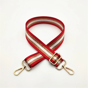 Détail d'une bandoulière rayée rouge et blanc avec mousquetons et boucle en métal doré