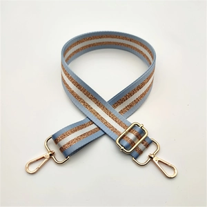 Détail de la bandoulière en tissu rayé bleu clair et blanc avec des fils dorés brillants