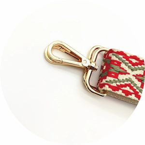 Close-up of ethnic geometric jacquard woven strap with golden metal lobster clasp