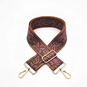 Close-up of ethnic paisley pattern bag strap with gold metal lobster clasps and buckle