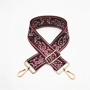 Close-up of ethnic style paisley pattern on burgundy adjustable shoulder strap with gold hooks