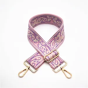 Close-up of pink paisley embroidered bag strap with golden rotating metal hooks
