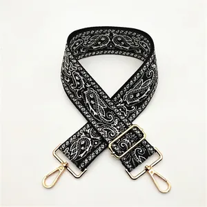 Detailed view of paisley pattern woven strap with gold metal lobster clasps and buckles