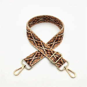 Close-up of ethnic style woven bag strap with golden metal lobster clasps and adjustment buckle
