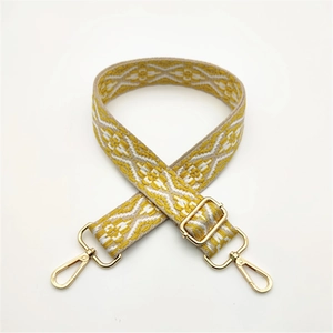 Close-up of adjustable woven shoulder strap with yellow geometric patterns and gold metal clips