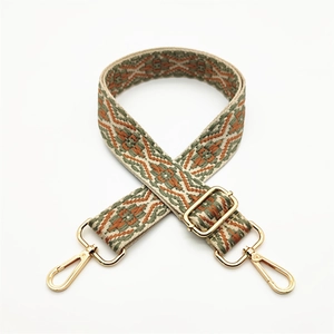 Detail of bohemian ethnic woven bag strap with green geometric patterns and gold metal clips