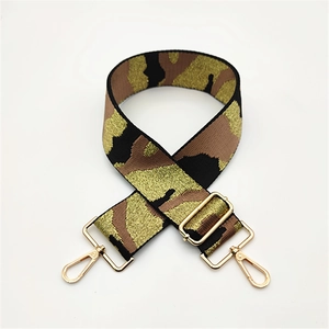 Detail of camouflage jacquard bag strap with gold threads and polished metal clasps