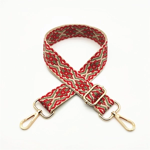 Close-up of adjustable woven canvas strap with ethnic red floral patterns and gold metal clips