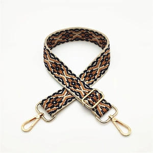 Detail of ethnic geometric woven strap with golden lobster clasps and metal buckle