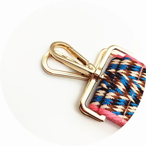 Detailed close-up of wide braided bag strap with gold metal lobster clasp and geometric pattern