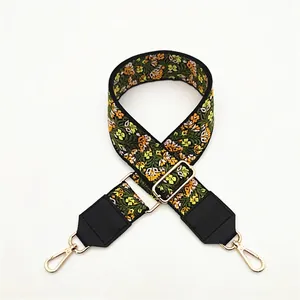 Detail view of ethnic floral embroidered wide strap with black leather ends and gold buckles