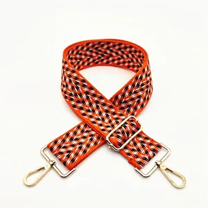 Detailed weave of geometric orange and black bag strap with gold metal lobster clasp