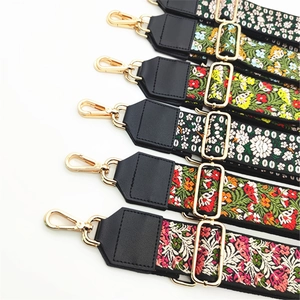 Close-up of ethnic floral embroidery bag straps with gold metal clasps and PU leather