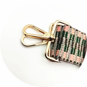 Détail de la sangle tissée avec motif à carreaux vert et rose et fermoir doré brillant