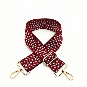 Detail view of red and black herringbone woven bag strap with golden adjustable metal buckle