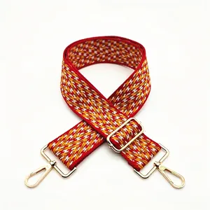 Detail of red and yellow zigzag woven bag strap with adjustable gold metal hardware