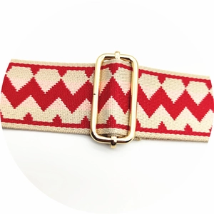 Detailed view of adjustable gold buckle on red and white diamond pattern bag strap