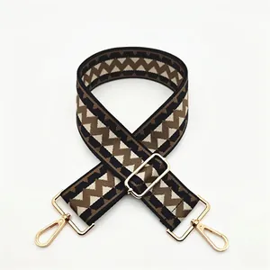 Detail of adjustable wide woven shoulder strap with geometric pattern and gold hardware