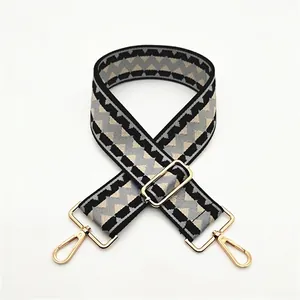 Detail of adjustable wide shoulder strap with black and grey geometric weave and gold clips