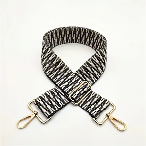 Détail de la bandoulière tissée noir et blanc avec fermoirs mousquetons dorés clairs