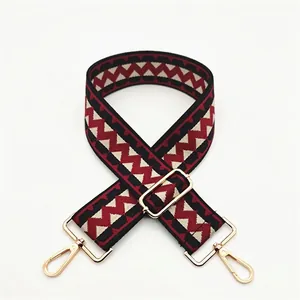 Close-up of red and black geometric zigzag pattern bag strap with gold metal buckles