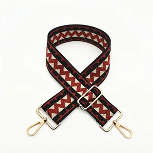 Detail of adjustable wide shoulder strap with red and black zigzag pattern and gold hooks