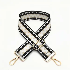 Close-up of wide geometric pattern strap with gold buckles and lobster clasps