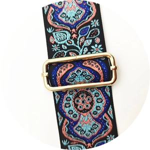 Macro detail of bohemian ethnic embroidered bag strap with gold metal adjustment buckle