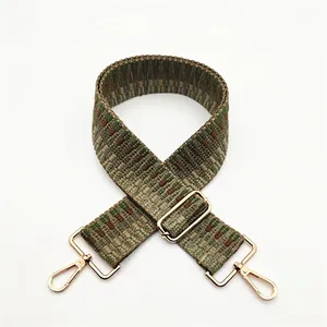 Detail of bohemian woven bag strap with green and brown geometric pattern and gold buckle