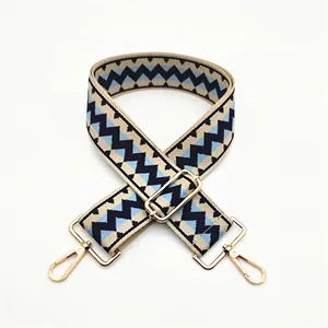Detail of wide adjustable chevron bag strap with navy blue pattern and gold metal hooks
