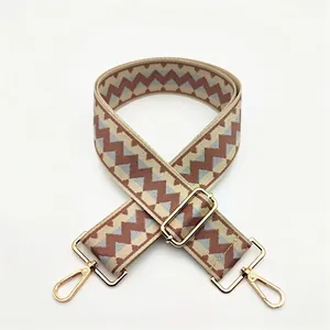 Detail of woven geometric shoulder strap with gold metal lobster clasps and buckle