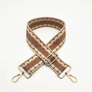Detail of adjustable geometric diamond pattern bag strap with gold metal buckles